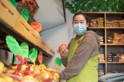 Masked store girl holds apple 